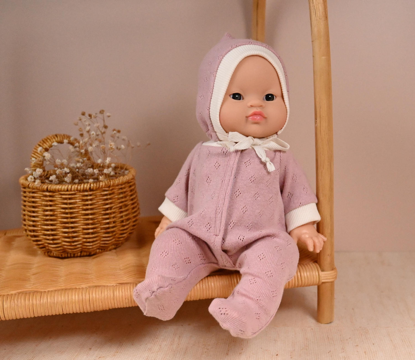 his cosy footed sleeper is made from soft, breathable cotton jersey in a beautiful dusty rose shade — perfect for keeping your doll snug and stylish.
The delicate eyelet knit pattern adds a vintage-inspired charm, while the ribbed cuffs and matching bonnet complete the look with comfort and care. Thoughtfully designed to fit 34cm dolls like Minikane and Paola Reina, it’s ideal for bedtime play and quiet cuddles.
Handmade from 100% Pointelle Cotton Jersey