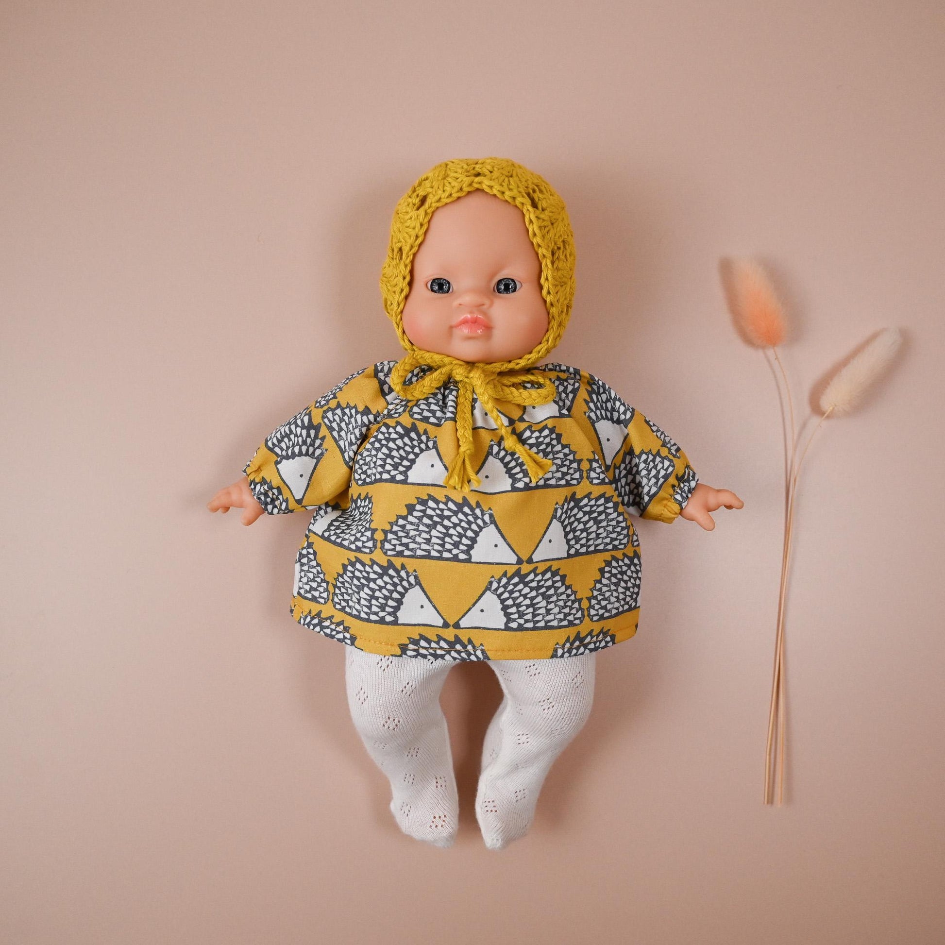 A cheerful outfit full of character and comfort! 🦔
This set includes a soft, long-sleeved cotton top featuring a charming hedgehog print in mustard tones — bold, fun, and perfect for woodland-inspired play. It’s paired with delicate white eyelet knit tights and a hand-crocheted mustard bonnet to keep your doll extra cosy and cute.