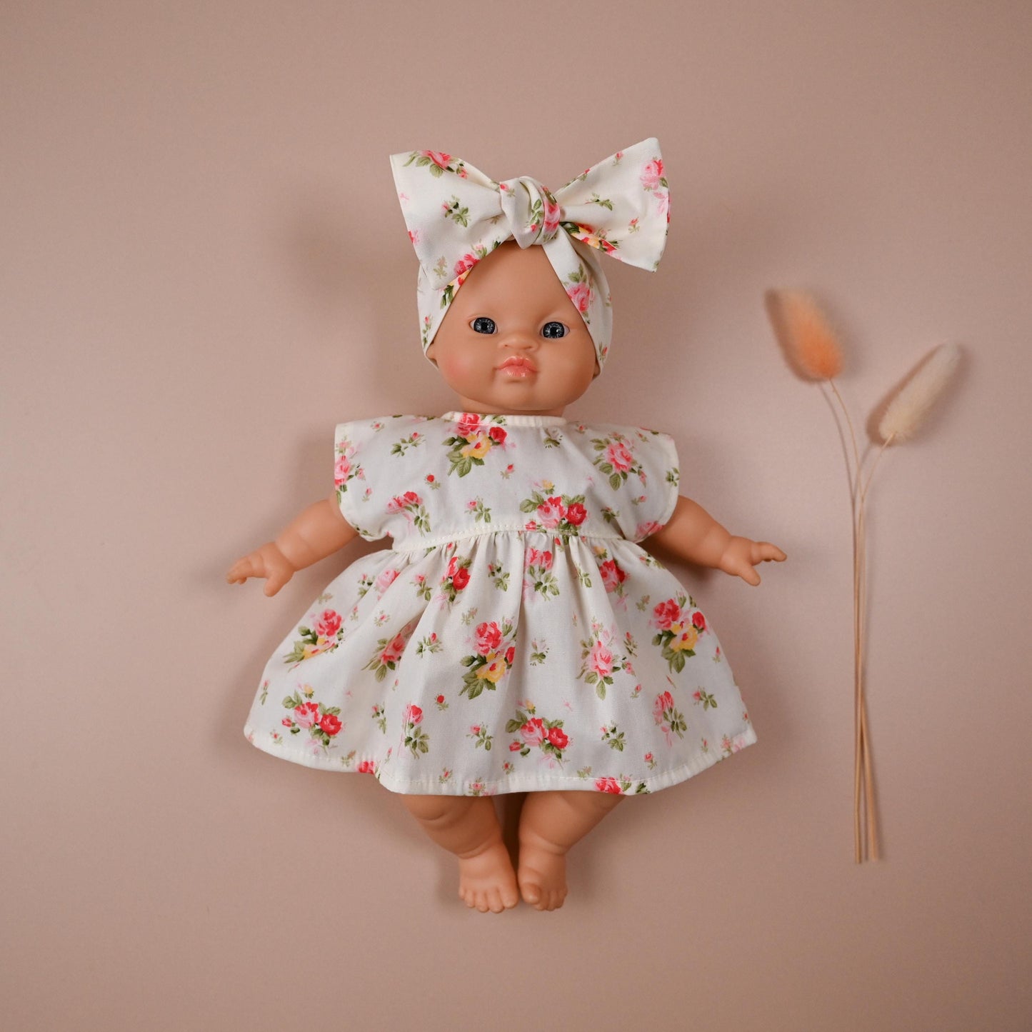 This sweet and summery set is full of timeless charm. The dress features a soft ivory background scattered with blooming vintage-style roses in shades of pink, red, and yellow — perfect for sunny strolls and tea party play.

The oversized matching bow headband adds a playful finish, completing a look that’s both classic and cheerful.