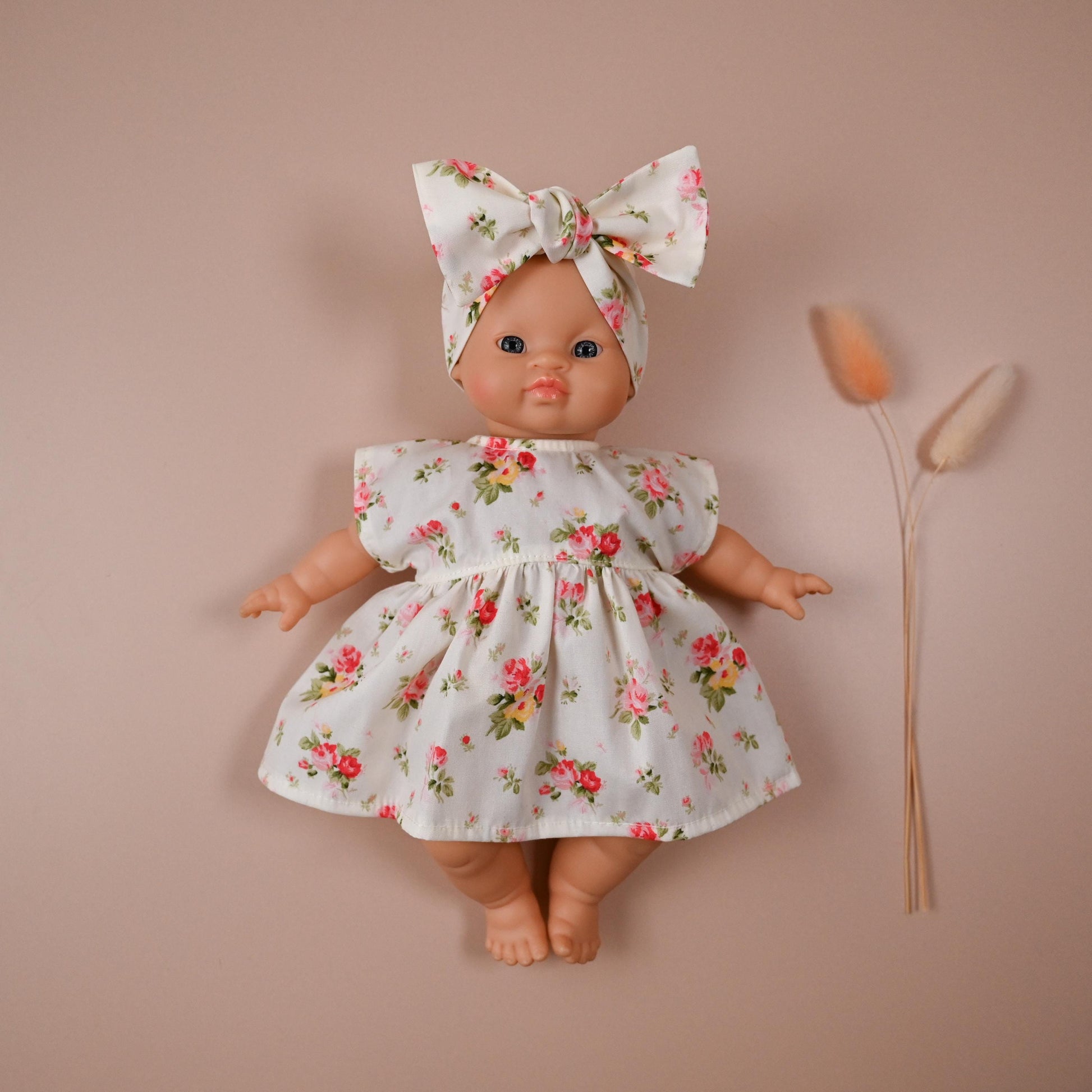 This sweet and summery set is full of timeless charm. The dress features a soft ivory background scattered with blooming vintage-style roses in shades of pink, red, and yellow — perfect for sunny strolls and tea party play.

The oversized matching bow headband adds a playful finish, completing a look that’s both classic and cheerful.