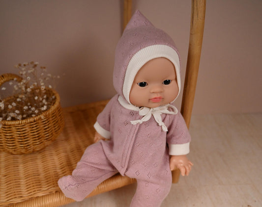 This cosy footed sleeper is made from soft, breathable cotton jersey in a beautiful dusty rose shade — perfect for keeping your doll snug and stylish.

The delicate eyelet knit pattern adds a vintage-inspired charm, while the ribbed cuffs and matching bonnet complete the look with comfort and care. Thoughtfully designed to fit 34cm dolls like Minikane and Paola Reina, it’s ideal for bedtime play and quiet cuddles.
Handmade from&nbsp; 100% Pointelle Cotton Jersey