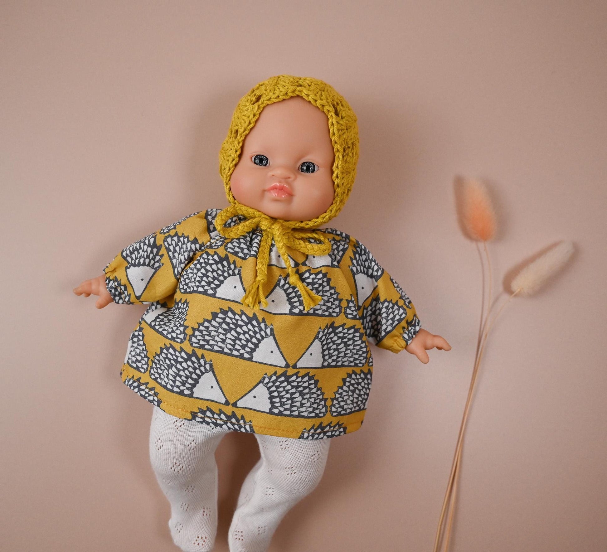 A cheerful outfit full of character and comfort! 🦔
This set includes a soft, long-sleeved cotton top featuring a charming hedgehog print in mustard tones — bold, fun, and perfect for woodland-inspired play. It’s paired with delicate white eyelet knit tights and a hand-crocheted mustard bonnet to keep your doll extra cosy and cute.